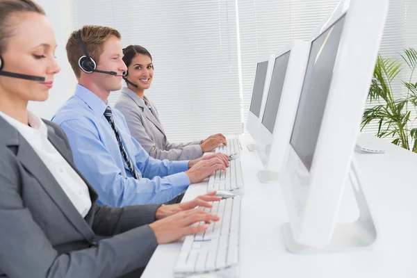 Equipe de negócios trabalhando em computadores e usando headsets — Fotografia de Stock