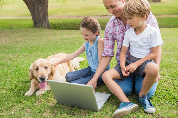 Happy family with their dog using laptop — Stock Photo, Image