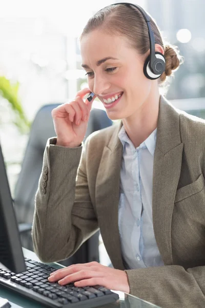 Donna d'affari sorridente con auricolare utilizzando i computer — Foto Stock