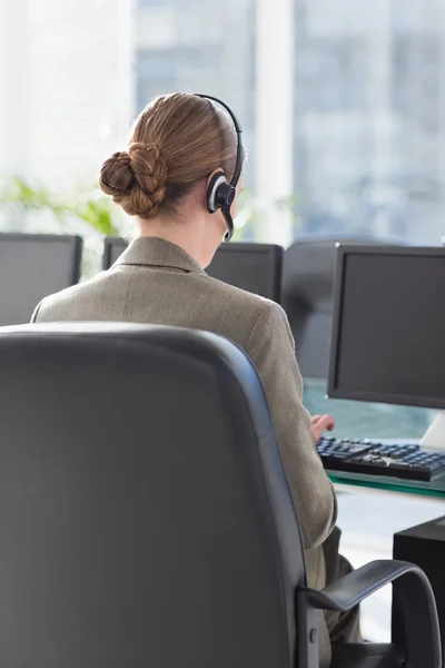 Leende affärskvinna med headset med datorer — Stockfoto