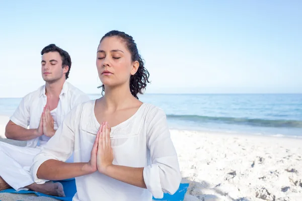 Happy couple doing yoga beside the water — Stock Photo, Image