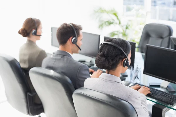 Pessoas de negócios com fones de ouvido usando computadores — Fotografia de Stock