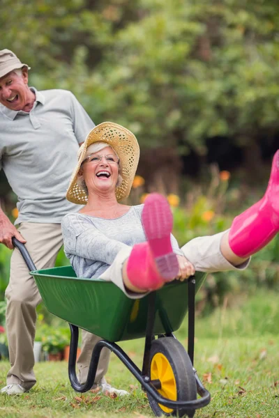 Gelukkige senior paar spelen met een kruiwagen — Stockfoto