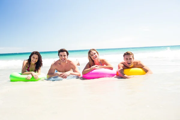 Happy friends lying on inflatable mattress above the water — Stock Photo, Image
