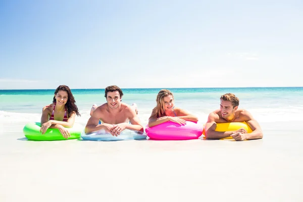 Happy friends lying on inflatable mattress above the water — Stock Photo, Image