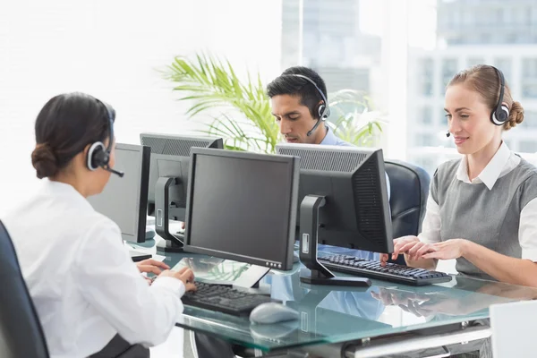 Mensen uit het bedrijfsleven met headsets met behulp van computers — Stockfoto