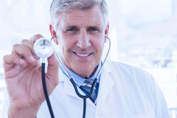 Kameraya gülümseyen ve onun stetoskop gösterilen mutlu doktor — Stok fotoğraf