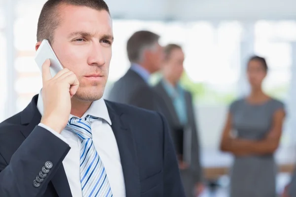 A telefon a kollégákkal, mögötte üzletember — Stock Fotó