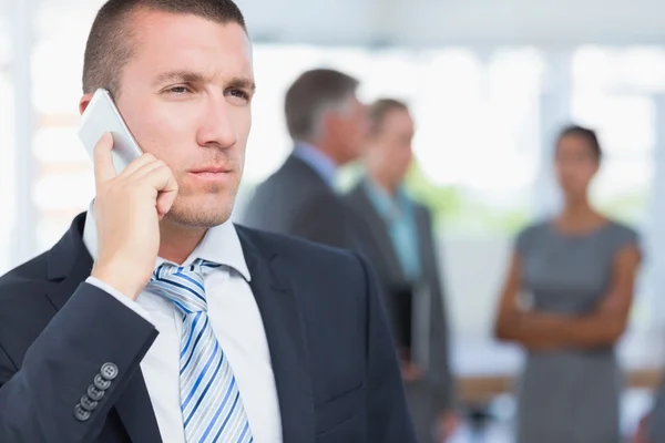 Empresário ao telefone com colegas que o apoiam — Fotografia de Stock