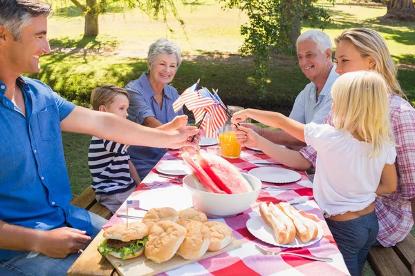 家族のピクニックを持つとアメリカの国旗を保持しています。 — ストック写真