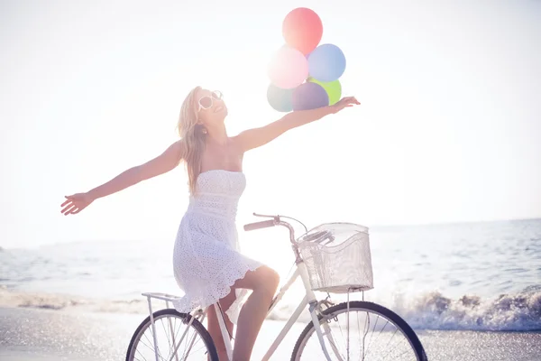 Blondin på cykeltur innehav ballonger — Stockfoto