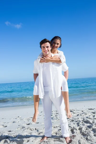 Handsome man giving piggy back to his girlfriend — Stock Photo, Image