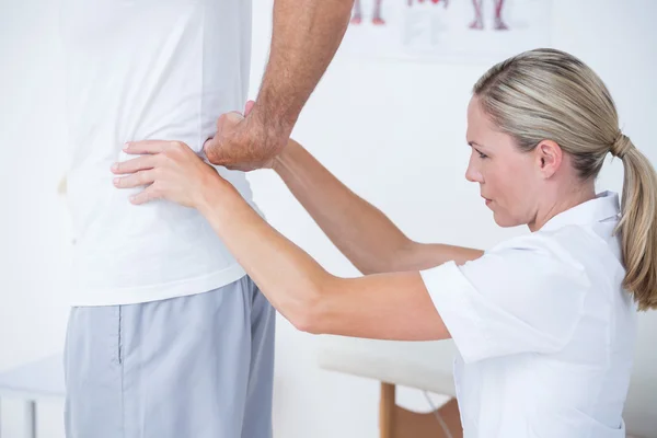 Läkaren undersöker hennes patienten tillbaka — Stockfoto