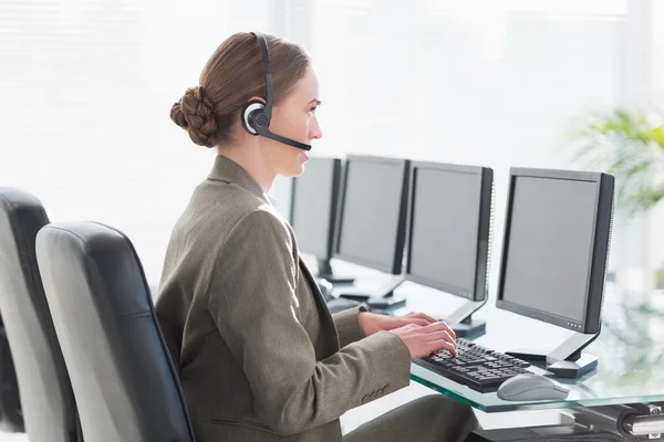 Glimlachende zakenvrouw met headset met behulp van computers — Stockfoto
