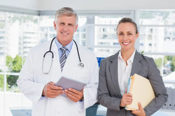 Médico de confianza y bonita mujer de negocios sonriendo a la cámara — Foto de Stock