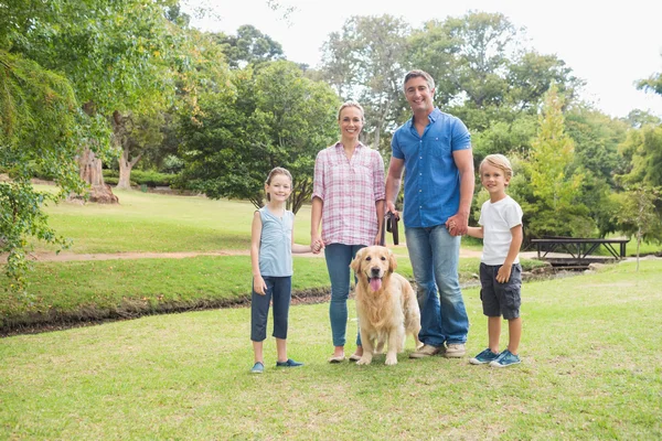 Família feliz sorrindo para a câmera com seu cão — Fotografia de Stock