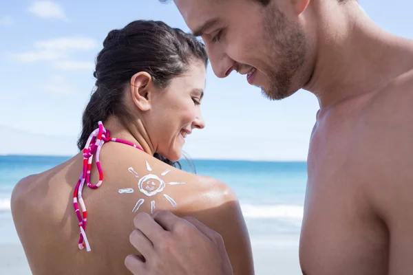 Knappe man zijn vriendin te zetten in de zon tan lotion — Stockfoto