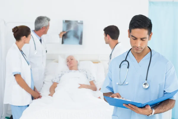 Report reading with colleagues and patient behind — Stock Photo, Image