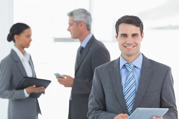 Affärsman med en tablett med kollegor bakom i office — Stockfoto