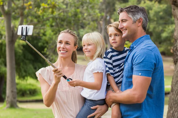 Szczęśliwa rodzina przy pomocy kija selfie w parku — Zdjęcie stockowe