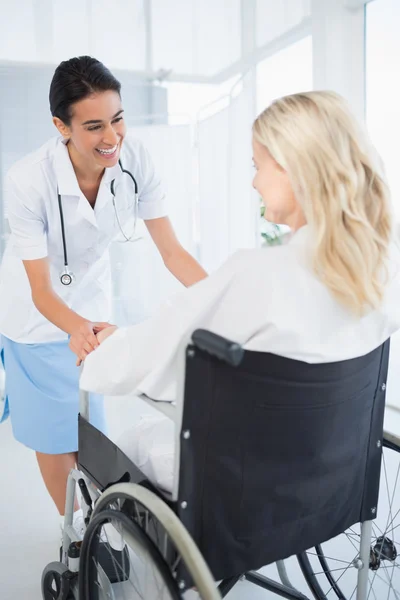 Happy doctor smiling at her patient in wheelchair — Stock Photo, Image