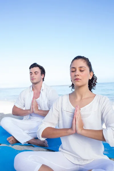 Pareja feliz haciendo yoga al lado del agua — Foto de Stock