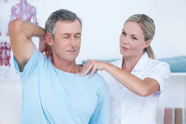 Médico esticando um braço de homem — Fotografia de Stock