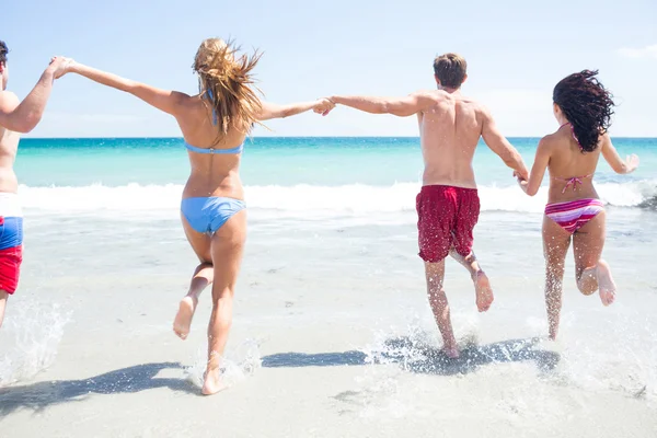 Amigos felices corriendo en el agua juntos — Foto de Stock