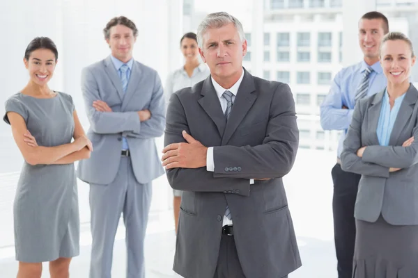 Smiling business team in piedi con le braccia incrociate — Foto Stock