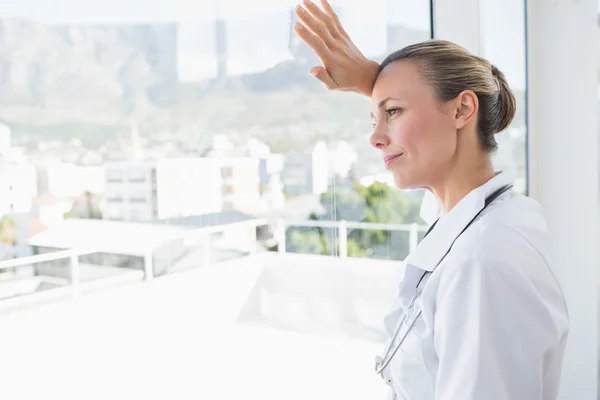 Vrouwelijke arts op zoek via windows — Stockfoto