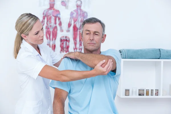 Doktor bir adam kol germe — Stok fotoğraf