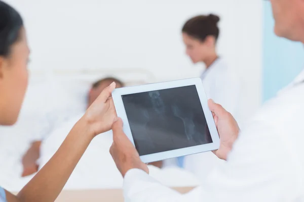 Arts met behulp van digitale tablet met collega's en patiënt achter — Stockfoto