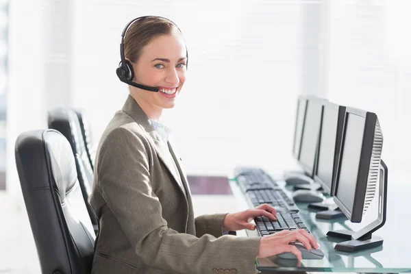 Femme d'affaires souriante avec casque utilisant des ordinateurs — Photo