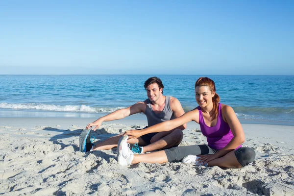 Happy couple stretching together beside the water — Stock Photo, Image