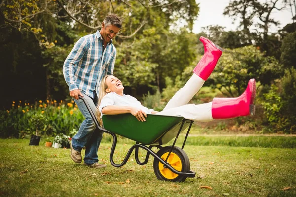 Happy couple playing with a wheelbarrow — Stock Photo, Image