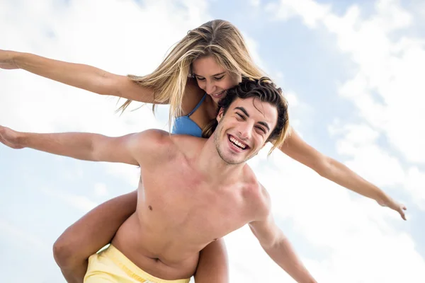 Handsome man giving piggy back to his girlfriend — Stock Photo, Image