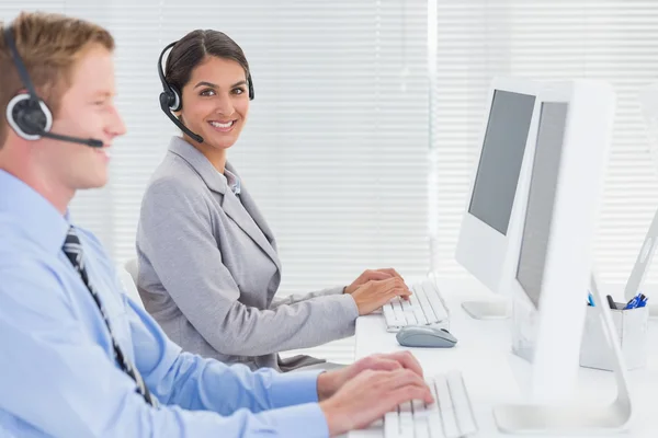 Business team working on computers and wearing headsets — Stock Photo, Image