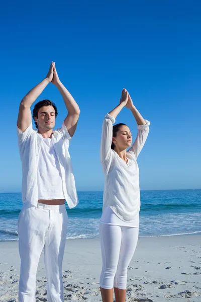 Pareja feliz haciendo yoga al lado del agua — Foto de Stock