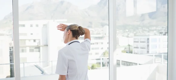Vrouwelijke arts op zoek via windows — Stockfoto