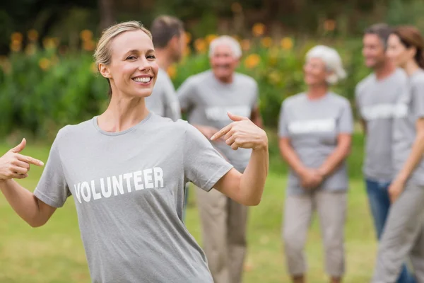 Voluntária feliz mostrando sua camiseta para câmera — Fotografia de Stock