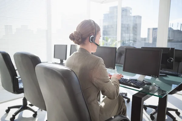 Smiling businesswoman with headset using computers — Stock Photo, Image