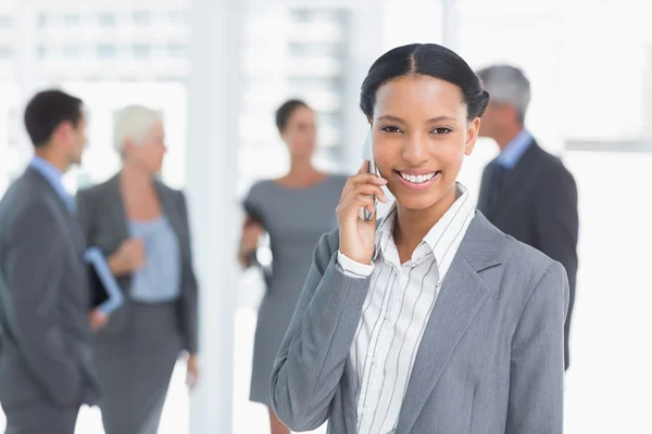 Empresária usando telefone celular com colegas por trás — Fotografia de Stock