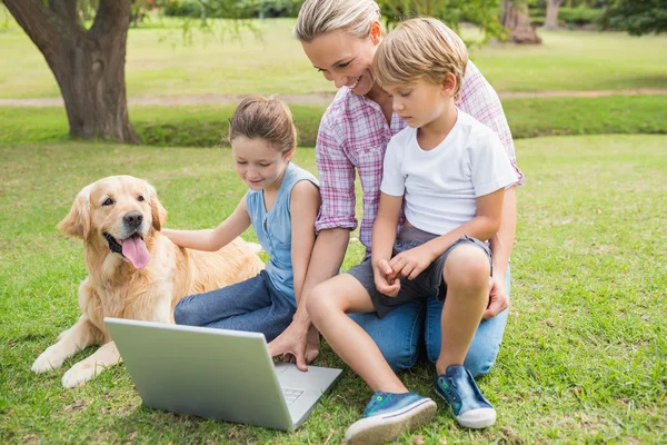 Famiglia felice con il loro cane utilizzando il computer portatile — Foto Stock