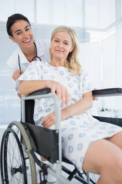 Läkare och patient i rullstol ler mot kameran — Stockfoto