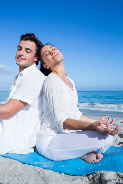 Happy couple doing yoga beside the water — Stock Photo, Image