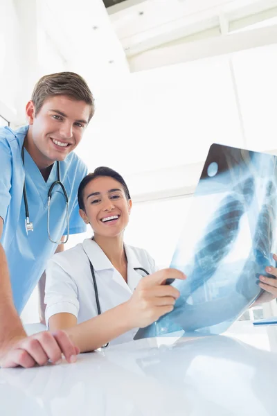 Médicos felices mirando la cámara y sosteniendo rayos X — Foto de Stock