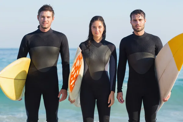 Friends in wetsuits with surfboard at beach — Stock fotografie