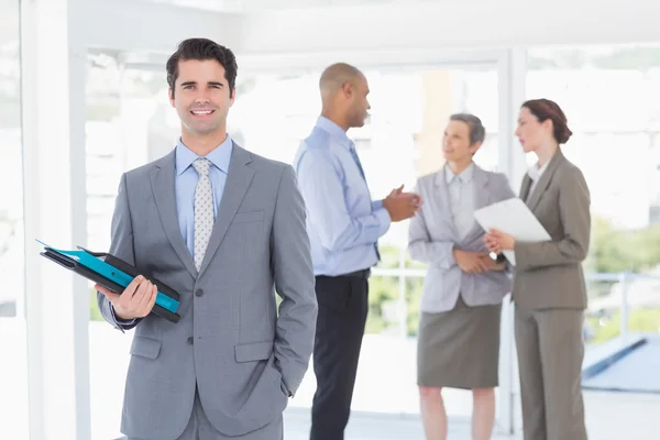 Smiling businessman holding files and looking at camera — Stock Photo, Image