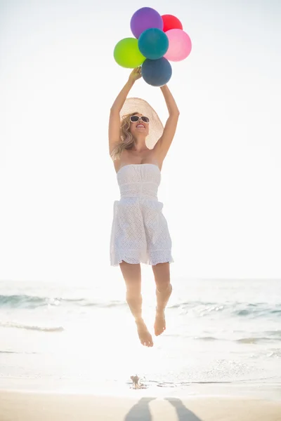 Woman holding baloons at beach — Stockfoto