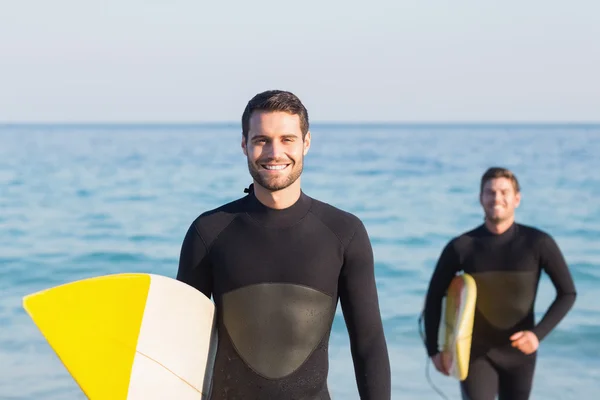 Mannen in wetsuits met surfboard op strand — Stockfoto